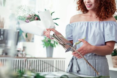 Pruner taşıyan ve sapları kurtulmak gülümseyen kısa saçlı kadın