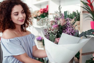Smiling cheerful lady checking her freshly-made bouquet clipart