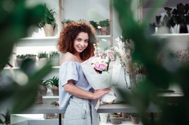 Atölyede parlak bir gün geçiren iyi görünümlü kıvırcık çiçekçi Işınlama