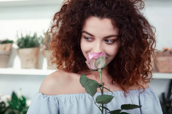 Beaming kręcone kobieta ciesząc się zapachem pięknej róży — Zdjęcie stockowe