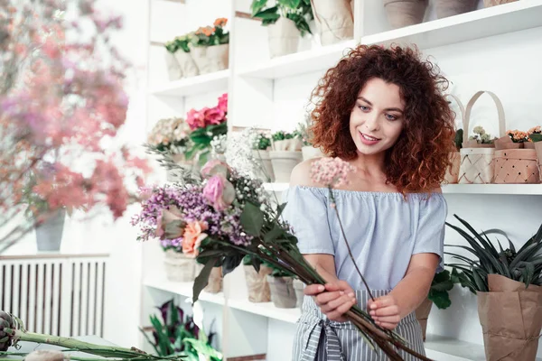 Sorridente dai capelli ricci bella ragazza scegliendo fiori per il suo capolavoro — Foto Stock