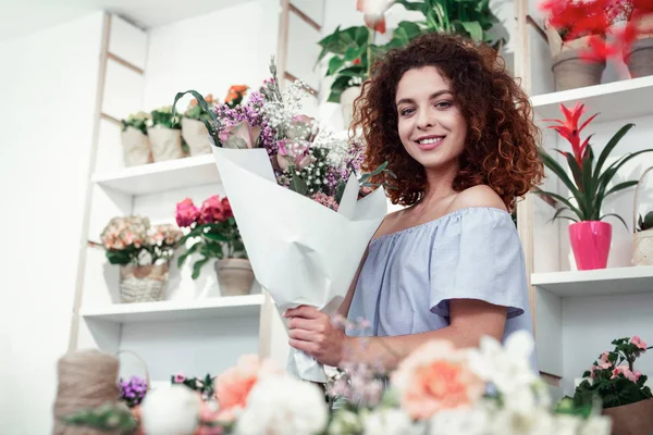 Orgullosa mujer rizada hermosa mostrando su excelente ramo — Foto de Stock