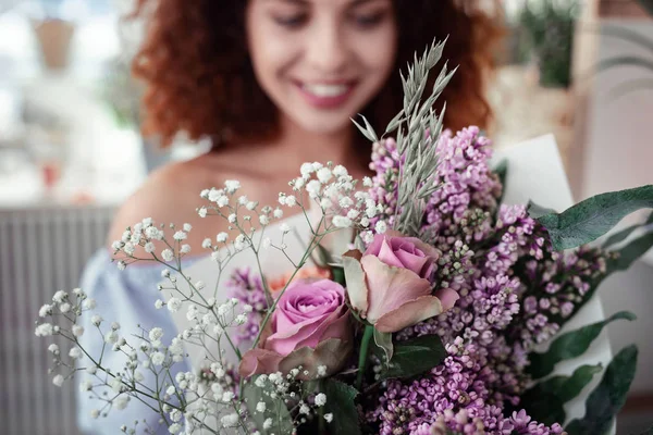 Aantrekkelijke jonge vrouw met gember haar houden voor haar lila boeket — Stockfoto