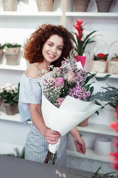 Memnun kıvırcık saçlı genç kız onu çiçek başyapıtı gösteren — Stok fotoğraf