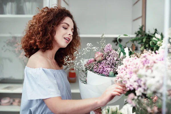 Привабливий кучерявий молодий флорист вибирає додаткові квіти для своїх букетів — стокове фото