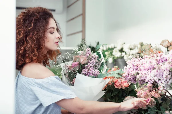 Özenli kısa saçlı kadın onun depolama sunulan çiçekler gözlemleyerek — Stok fotoğraf