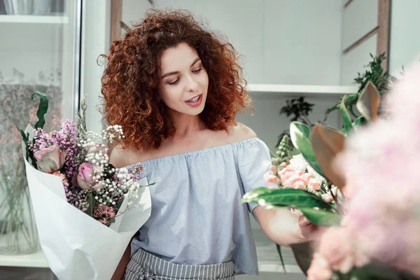 Interessato dai capelli ricci giovane signora toccare steli di fiori freschi — Foto Stock