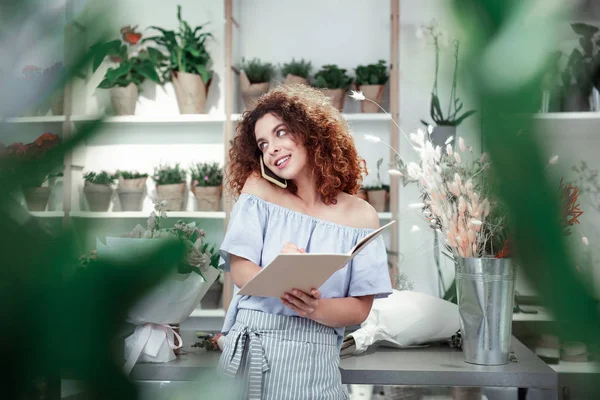 Vrolijke roodharige meid schrijft informatie in notebook — Stockfoto