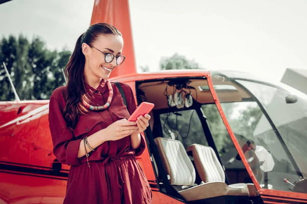 Woman wearing glasses texting man waiting for him near helicopter