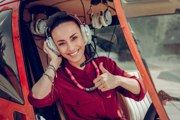 Helikopterde başarılı uçuştan sonra geniş bir şekilde gülümseyen kara gözlü kadın — Stok fotoğraf
