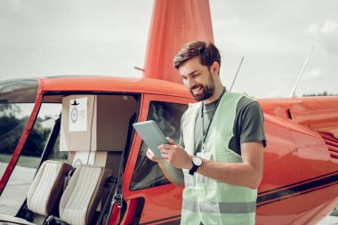 Sakallı gönüllü uçmadan önce tablet ile helikopter in yanında duruyor