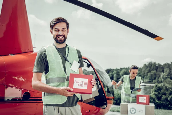 Humanitární důstojník stojící poblíž malého červeného vrtulníku s kolegou — Stock fotografie