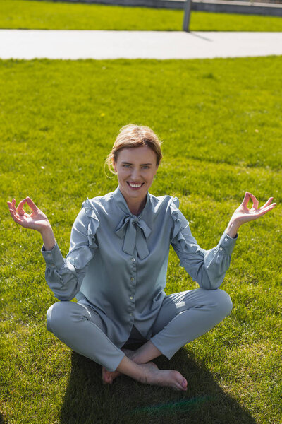 Officially dressed woman meditating on the grass