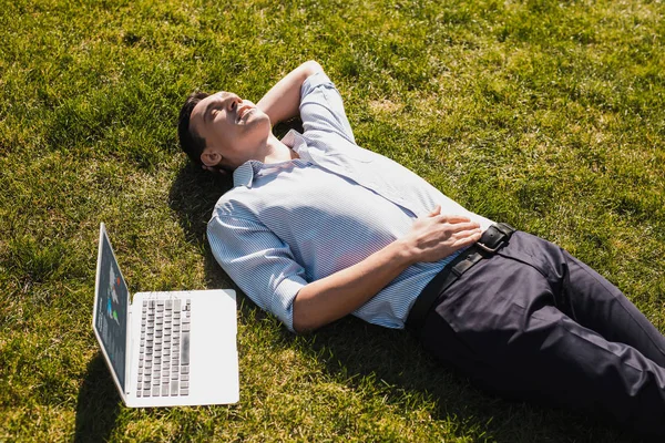 Чоловік відпочиває на траві, працюючи дистанційно — стокове фото
