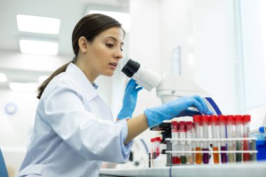 Dikkatli genç mikrobiyolog destekten test tüpü alıyor