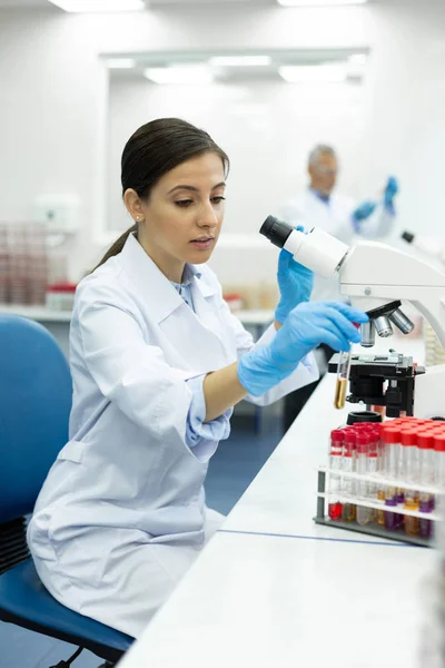 Pretty young chemist looking at test tube — Stock Photo, Image