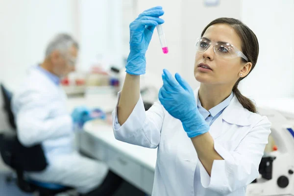 Attente brunette medische werker die roze vloeistof controleert — Stockfoto