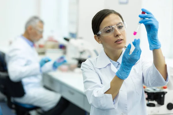 Científico joven serio haciendo experimento químico en laboratorio — Foto de Stock