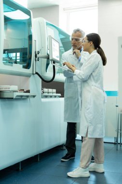 Büyük bilgisayarın yanında duran özenli laboratuvar çalışanları