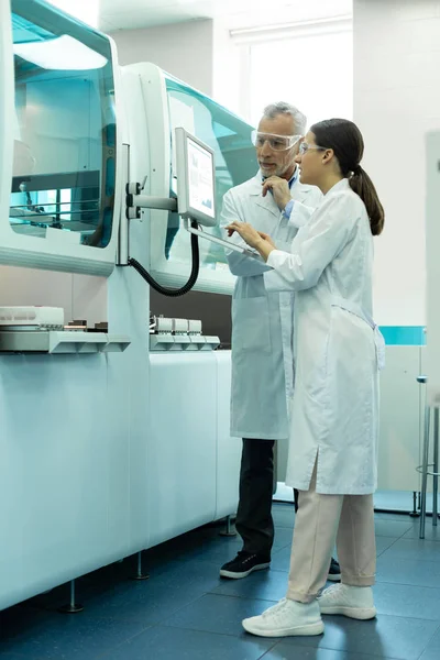 Trabajadores de laboratorio atentos de pie cerca de la computadora grande — Foto de Stock