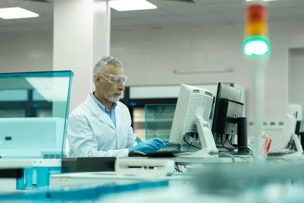 Geconcentreerde volwassen wetenschapper staren op het scherm van de computer — Stockfoto