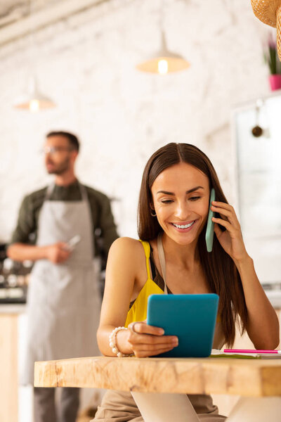 Wife calling clients while helping husband with business