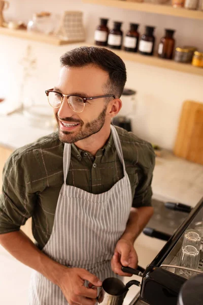 Handsome man smiling while making coffee for customer