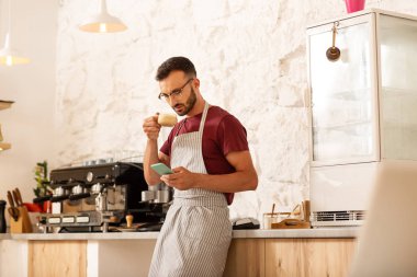 İşadamı kahve içiyor ve akıllı telefonda mesajları okuyor