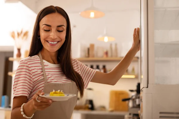 Serveuse de la cafétéria tenant assiette avec petit gâteau — Photo