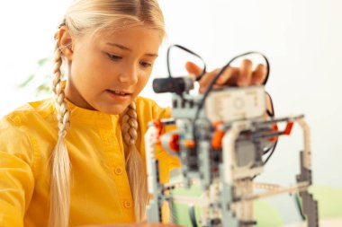O yapılan robot ile oynarken odaklanmış kız öğrenci.