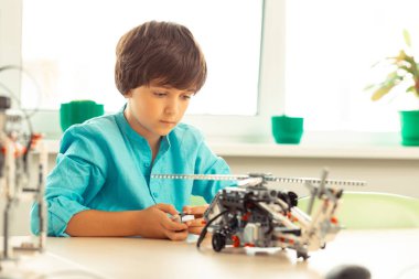 Konsantre öğrenci bir helikopter modeli dönüm.