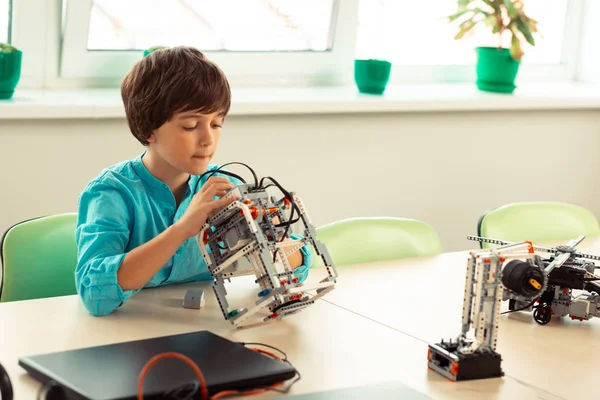 Concentrated schoolboy looking for mistakes in his robot model. — Stock Photo, Image