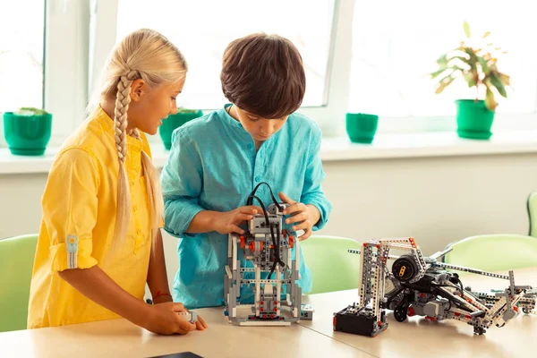 Menina e menino construindo um pequeno robô juntos . — Fotografia de Stock