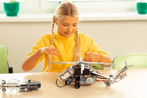 Concentrated schoolgirl turning on her helicopter model. — Stock Photo, Image