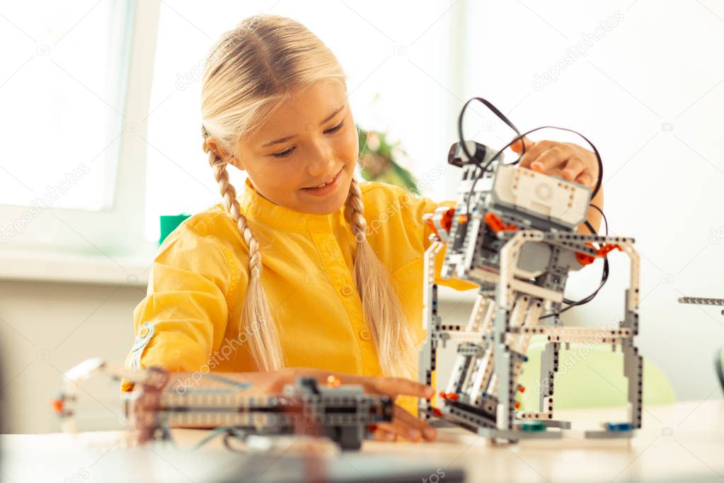Girl playing with a robot at science lesson.