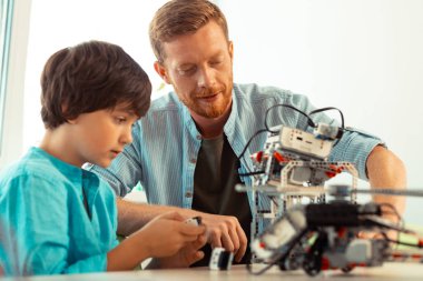 Bir öğrencinin robotu çevirmesi için destek veren öğretmen.