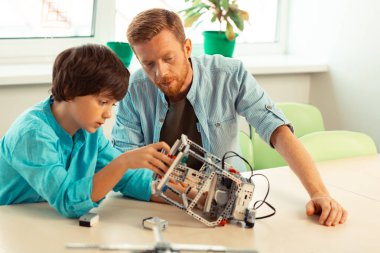 Öğretmeninin gözetiminde bir robot inşa öğrenci.