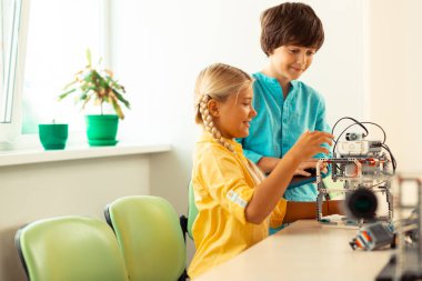 Yaptıkları robotla oynayan iki sınıf arkadaşı.