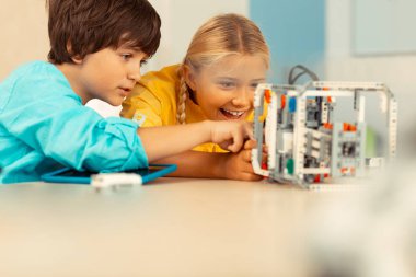 Bilim dersinde robotla oynayan heyecanlı çocuklar.