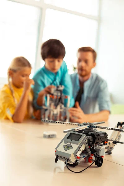 Dos alumnos trabajando en robot con su profesor . — Foto de Stock