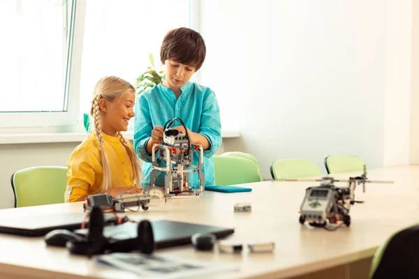 Muchacho mostrando a su compañero de clase la forma de construir un robot . — Foto de Stock