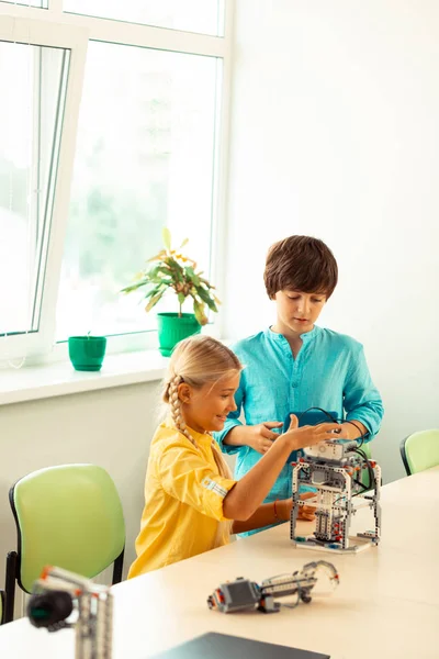 Ragazza e ragazzo accendere un robot a lezione di scienza . — Foto Stock