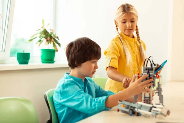 Fille aider son camarade de classe construire un robot . — Photo