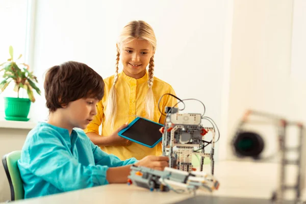 Ragazza in piedi vicino al suo compagno di classe costruendo un robot . — Foto Stock