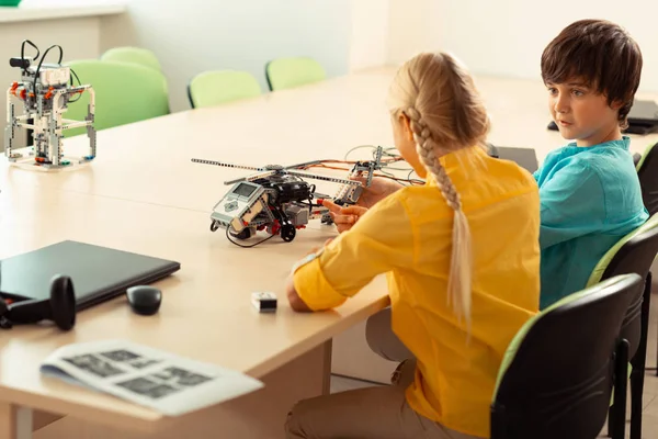 Sınıf arkadaşına bakarak şaşıran çocuk ona projesini anlatıyor.