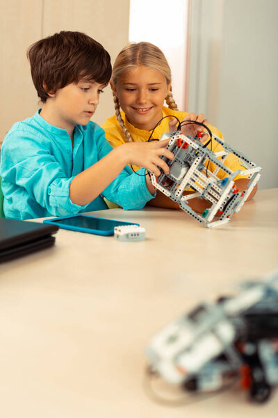 Two schoolchildren building a robot at science class.