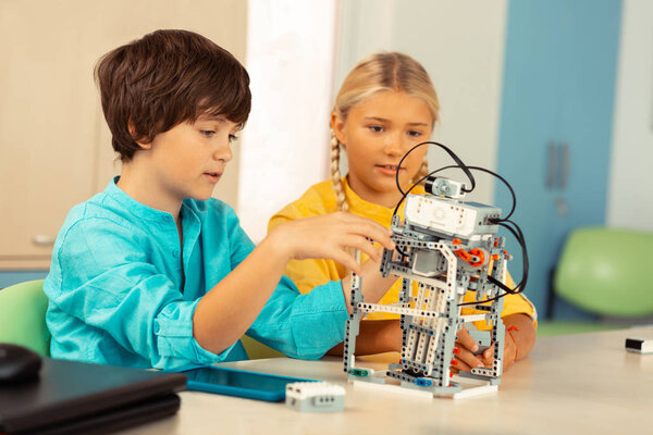 Boy explaining his classmate principals of working of his project.