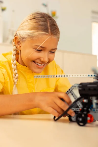 Chica sonriendo construyendo un modelo de helicóptero en la lección . — Foto de Stock