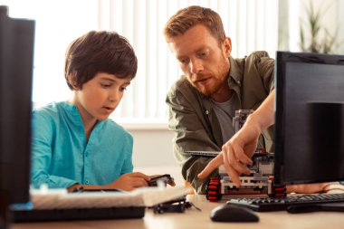 Öğretmen bir öğrenciye projedeki hatalarını gösteriyor.