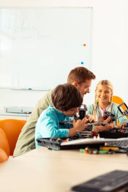 Öğrencilerine robot oluşturma yollarını gösteren öğretmen.